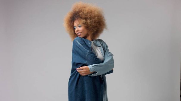 portret van gemengde ras zwarte vrouw met afro haar draagt een denim oversize shirt - Foto, afbeelding