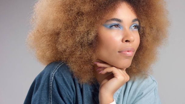 portrait of mixed race black woman with afro hair wears a denim oversize shirt - Foto, Imagen