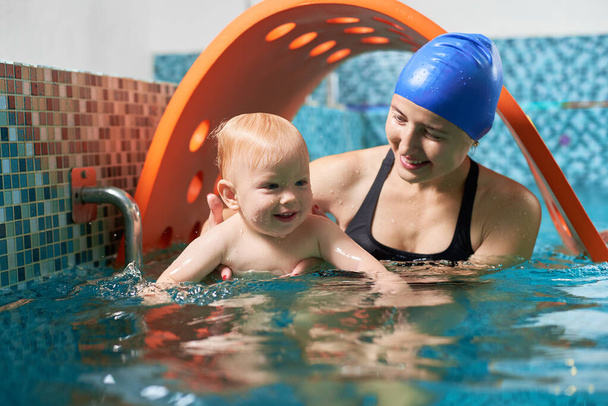 Bardzo ciekawy aktywny trening w basenie. Mały słodki chłopiec uczy się pływać ze swoją wspierającą matką. Pojęcie zdrowej rodziny - Zdjęcie, obraz
