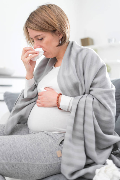 Pregnant woman catching cold, flu, virus, sitting at home on a c - Photo, Image