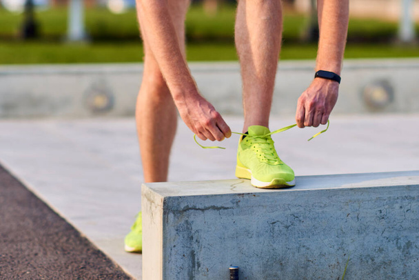 Giovane uomo moderno legare scarpe da corsa in un parco urbano
. - Foto, immagini