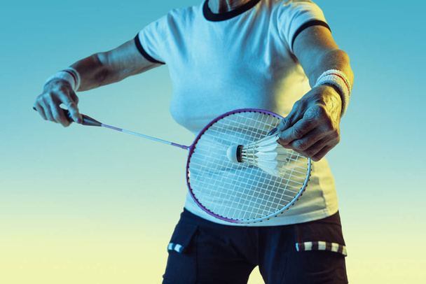 Senior woman playing badminton in sportwear on gradient background in neon light - Photo, Image