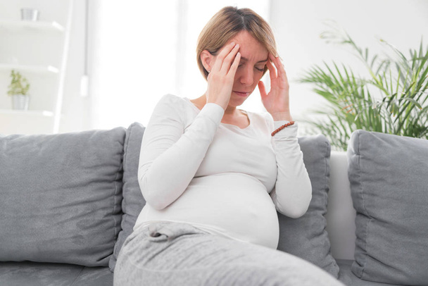 Schwangere müde erschöpfte Frau mit Magen- und Kopfproblemen bei h - Foto, Bild