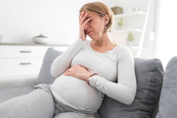 Schwangere müde erschöpfte Frau mit Magen- und Kopfproblemen bei h - Foto, Bild