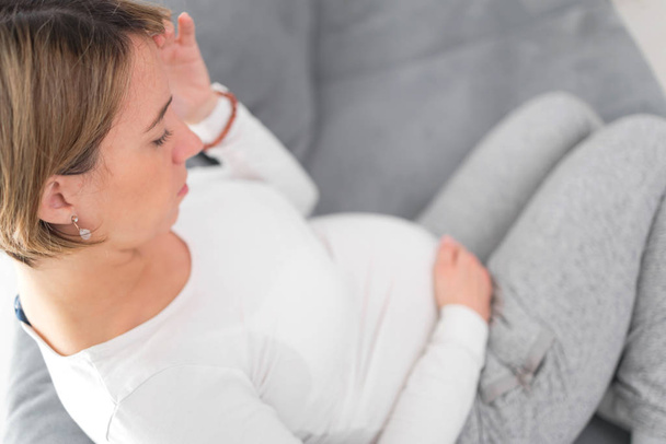Беременная уставшая от усталости женщина с проблемами с желудком и головой в час
 - Фото, изображение
