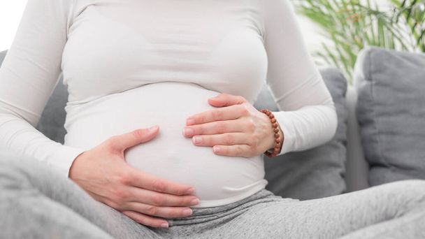 schwangere müde erschöpfte Frau mit Magenproblemen zu Hause auf einem  - Foto, Bild