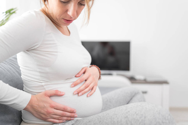 Έγκυος κουρασμένος εξαντλημένη γυναίκα με προβλήματα στο στομάχι στο σπίτι σε ένα  - Φωτογραφία, εικόνα
