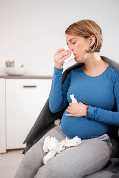 Femme enceinte attrapant froid, grippe, virus, assis à la maison sur un c
 - Photo, image