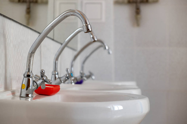White ceramic washing basins with shiny stainless steel water ta - Photo, Image