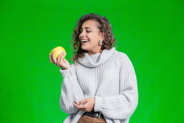 Organic food concept. Smiling female looking at a yellow apple with temptation and geat desire to bite it. - Foto, Bild