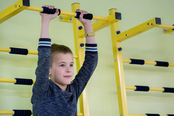 Young child boy exercising on a wall ladder bar inside sports gy - Photo, Image