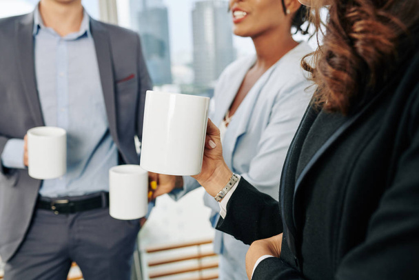 Businesswoman with big mug of coffee talking and gossiping with her coworkers during break - Zdjęcie, obraz