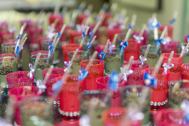 Close-up van transparante bekers met chocolade en plastic lepel met blauwe strik op kinderfeestje. Selectieve focus. - Foto, afbeelding