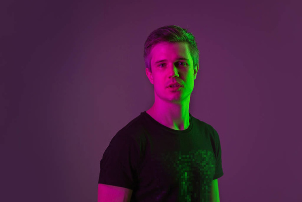 Caucasian mans portrait isolated on purple studio background in neon light - Foto, imagen