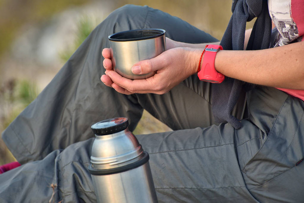 turista com uma garrafa térmica. mulher derrama chá sobre a natureza. menina na rocha
 - Foto, Imagem