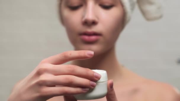 Woman in towel putting cream on face. - Filmagem, Vídeo