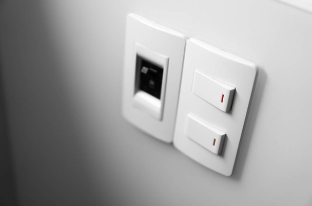 Interruptor blanco en una pared blanca con dos interruptores y un interruptor común
. - Foto, imagen