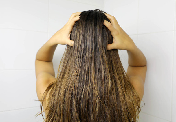 Νεαρή γυναίκα που βάζει λάδι στα μαλλιά με τα δάχτυλά της. Λάδι μαλλιών befo - Φωτογραφία, εικόνα