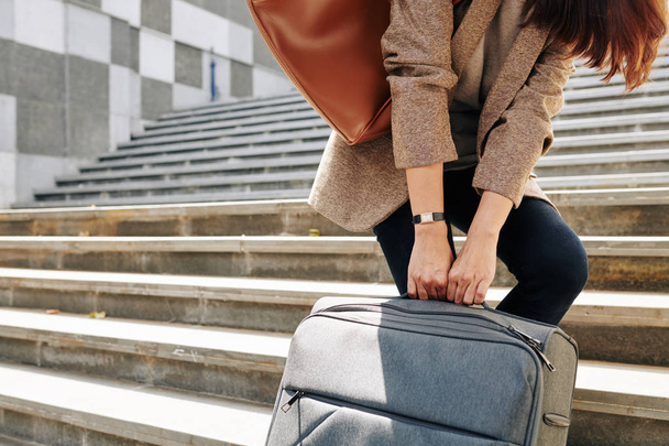 Cropped image of woman pulling big suitcase when walking up the stairs to railway station - Zdjęcie, obraz