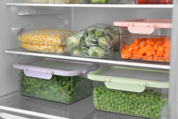 Plastic bags and containers with different frozen vegetables in refrigerator - Foto, Imagem