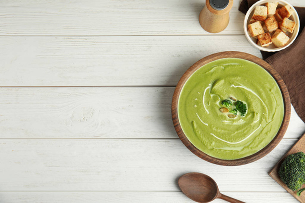 Delicious broccoli cream soup served on white wooden table, flat lay. Space for text - Fotó, kép