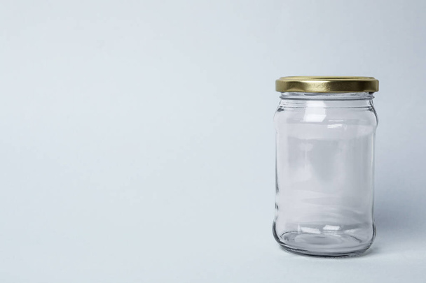 Closed empty glass jar on light background, space for text - Fotoğraf, Görsel