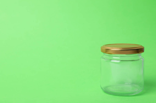 Closed empty glass jar on light green background, space for text - Foto, Bild