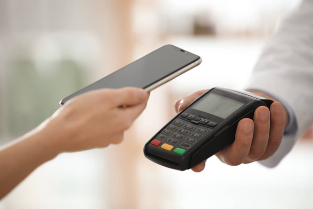 Customer using terminal for contactless payment with smartphone  - Foto, imagen