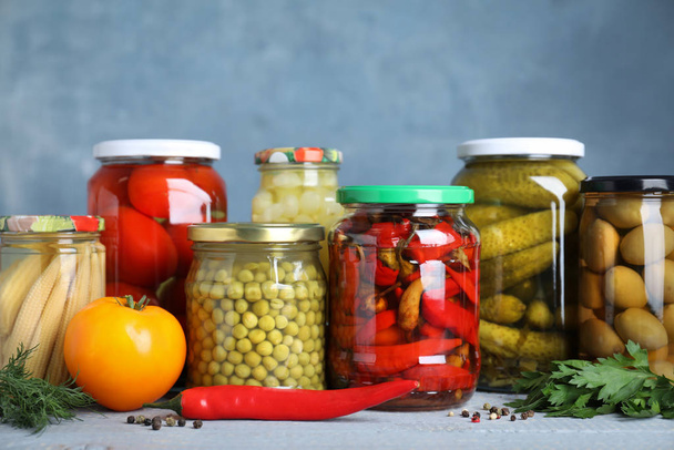 Glass jars with different pickled vegetables on table - Fotoğraf, Görsel