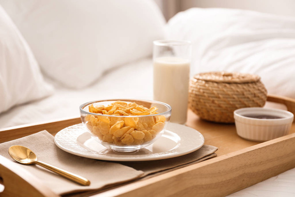 Corn flakes and milk in tray on bed.  Delicious morning meal - Фото, изображение