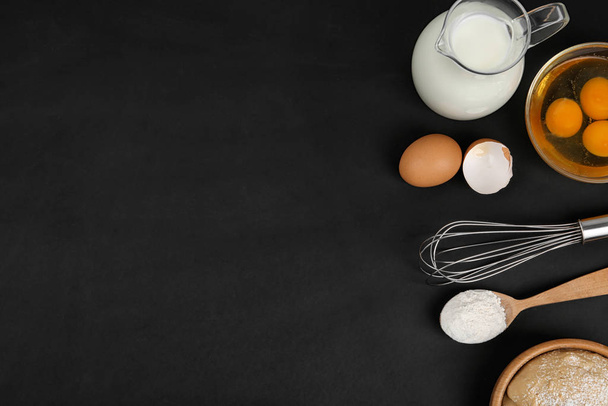 Flat lay composition with raw eggs and other ingredients on black background, space for text. Baking pie - Photo, image