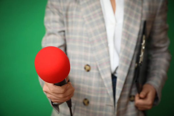 Δημοσιογράφος με μικρόφωνο και πρόχειρο σε πράσινο φόντο, closeup - Φωτογραφία, εικόνα