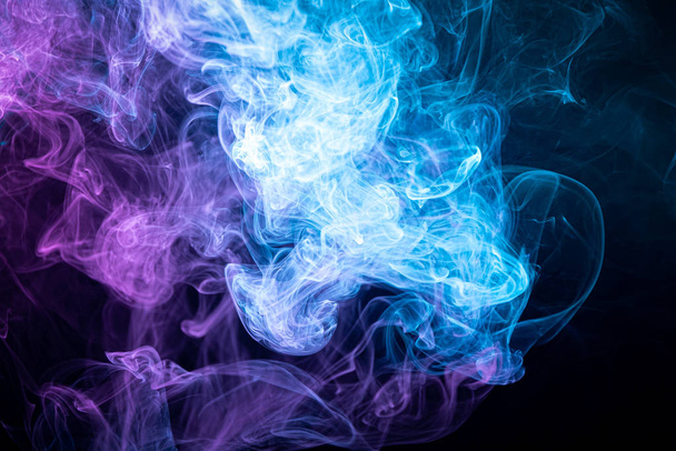 Abstract art pink and blue colored smoke on black isolated background. Stop the movement of multicolored smoke on dark backgroun - Photo, Image