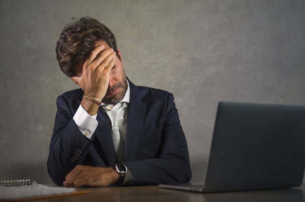 déprimé et stressé attrayant homme d'affaires hispanique en costume et cravate de travail épuisé au bureau ordinateur frustré et surchargé de travail en tant qu'homme d'affaires en difficulté
 - Photo, image