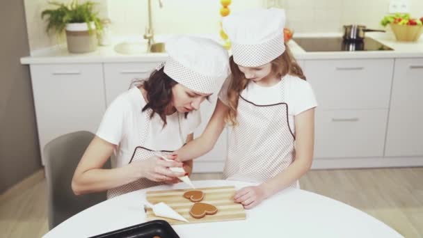 Beautiful mother teaching pretty child how to cook biscuits - Filmmaterial, Video