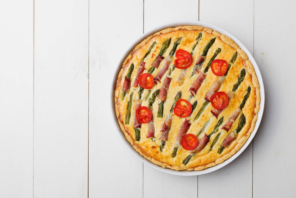 Tart with asparagus and tomatoes on white wooden background. - Foto, Bild