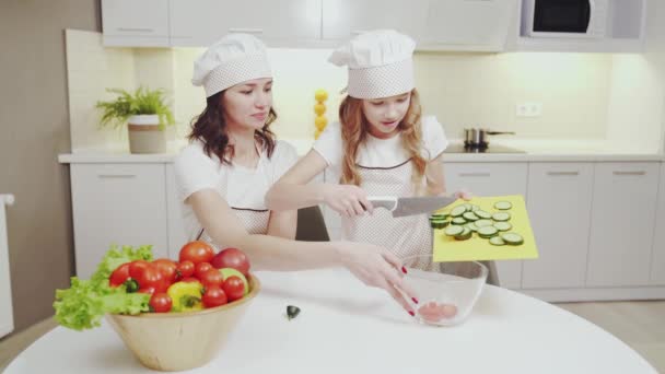 Happy mother and daughter cooking vegetable salad together - Filmagem, Vídeo