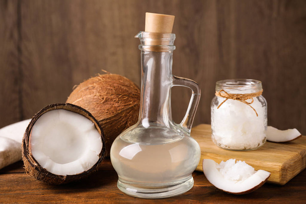 Coconut oil in glass jug on wooden table - Fotó, kép