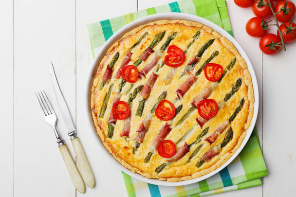 Tart with asparagus and tomatoes on white wooden background. - Photo, image