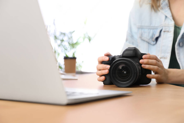 Professional photographer with camera working at table in office - Foto, Imagen