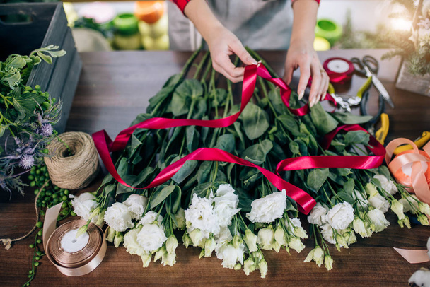 top view on female hands tying flowers in red ribbon - Fotografie, Obrázek