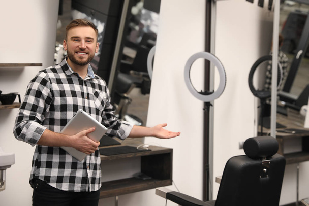 Young business owner with tablet in barber shop - Valokuva, kuva