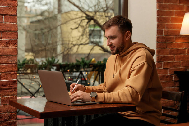 Male blogger working with laptop at table in cafe - Foto, imagen
