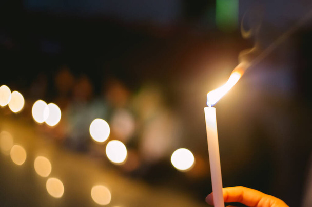 мягкий фокус людей, зажигающих свечи в темноте в поисках надежды, поклонения, надежды - Фото, изображение