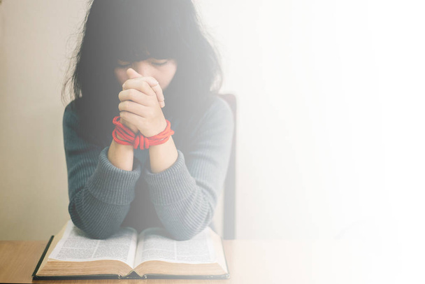 Jonge vrouw zitten en bidden op bijbel.Kopieer ruimte - Foto, afbeelding