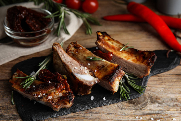 Tasty grilled ribs with rosemary on wooden table - Фото, изображение