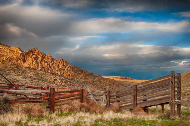 Rampa de carga de ganado de madera se encuentra en el lado sombreado de las colinas
 - Foto, imagen