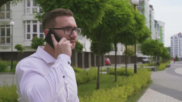 Bearded man talking on smartphone outdoors. - Video