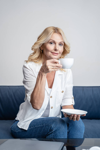 Smiling middle-aged lady drinking tea at home - Fotoğraf, Görsel