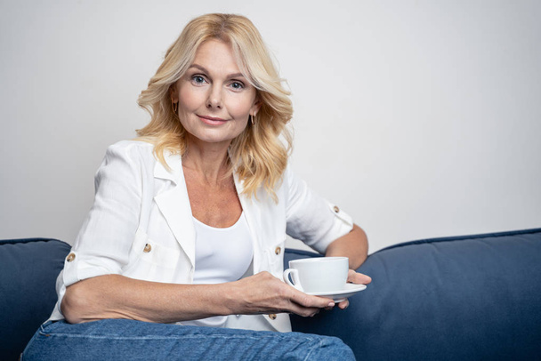 Pleased pretty woman drinking coffee at home - Fotografie, Obrázek